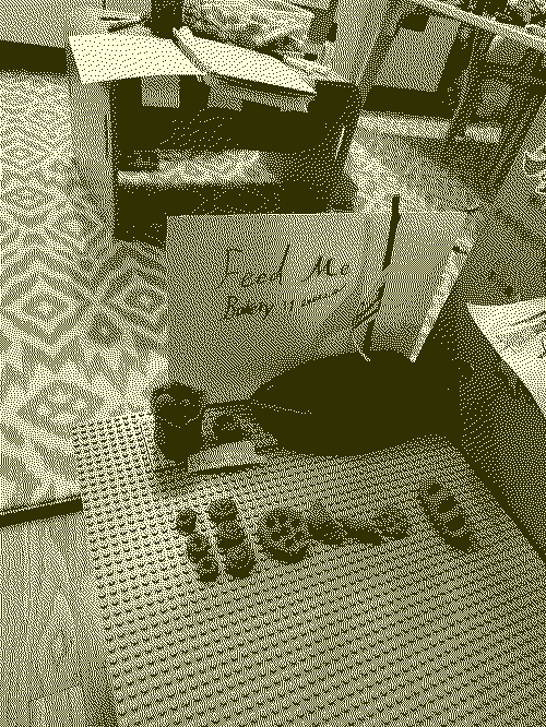 dithered image of a DIY bakery with various baked goods made of modeling clay -- doughnuts, cinnamon rolls, a pepperoni pizza (hey, it's baked and it's a good), croissants, baguette