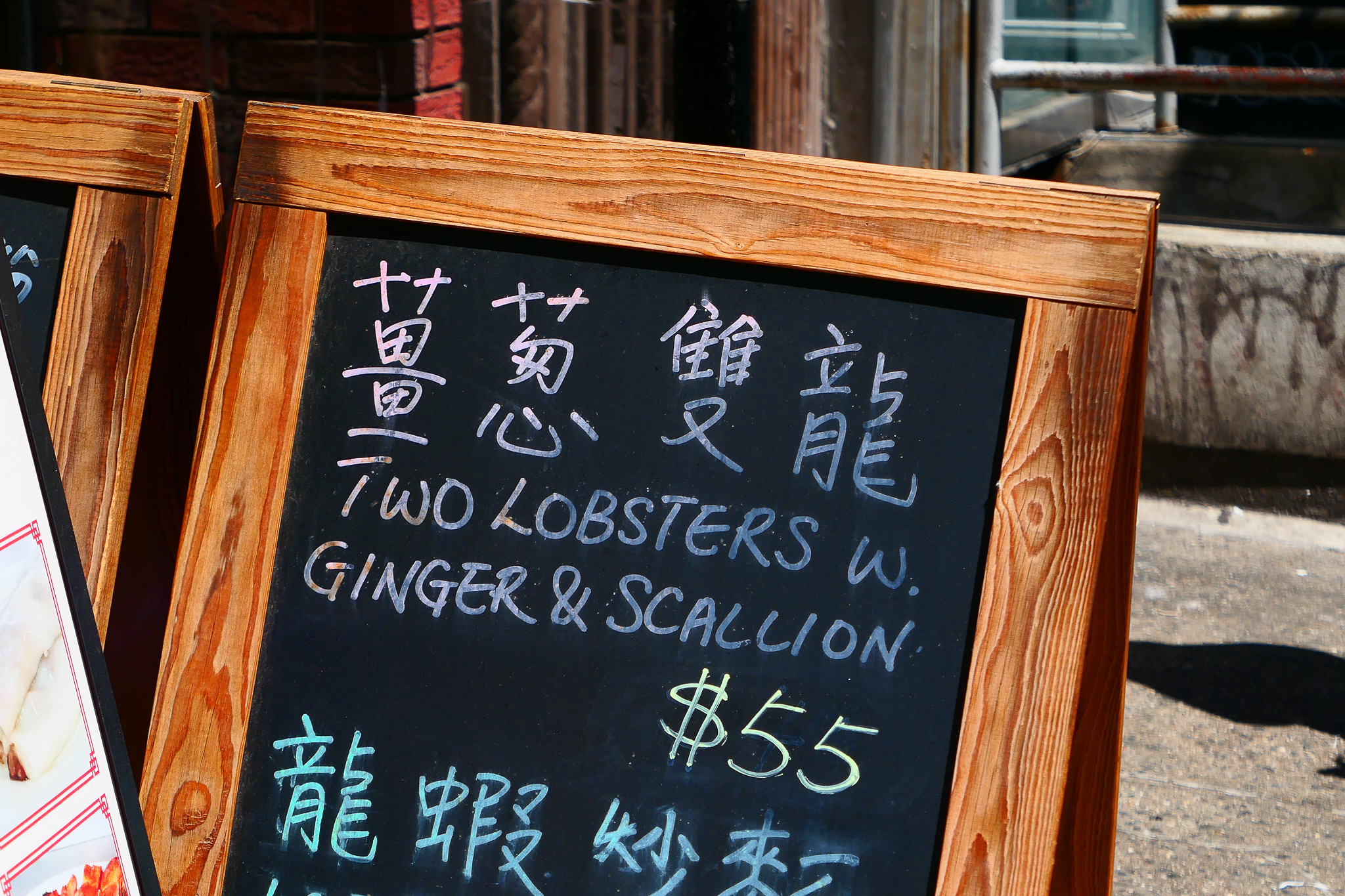 Handwritten lettering on a blackboard: 'Two lobsters w. ginger and scallion $55'