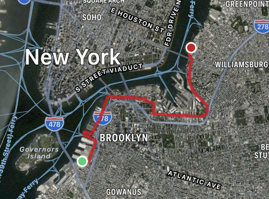 Screenshot of a satellite map view zoomed into north Brooklyn, with a red line mapping a bike route snaking along the East River from Brooklyn Bridge Park to Domino Park